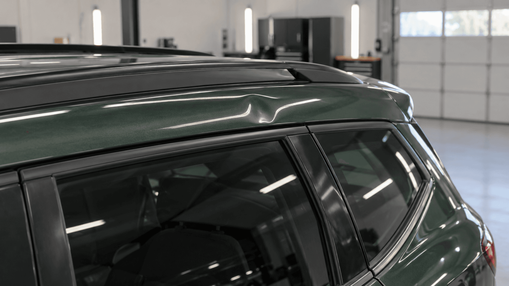 Small roof-rail dent on a forest green crossover before repair